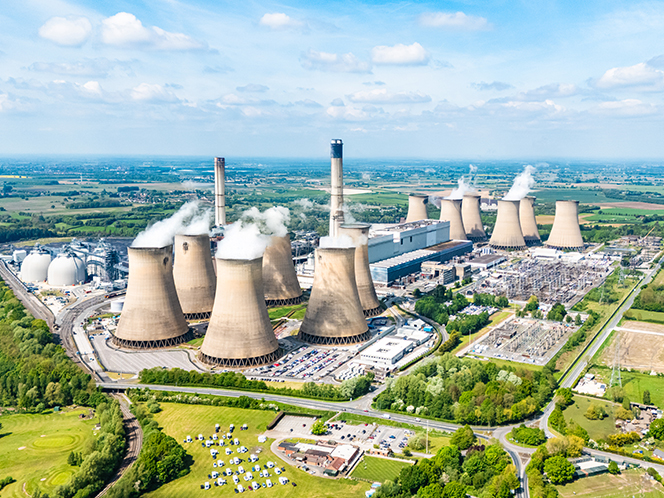 A power station billowing smoke into the air surrounded by green land